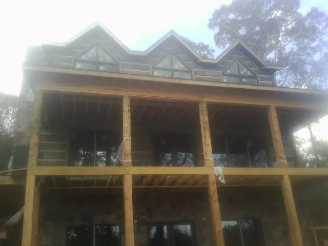 Dormers and porch framing on a large log home under construction — Roof Coating work by our crew in Neshkoro