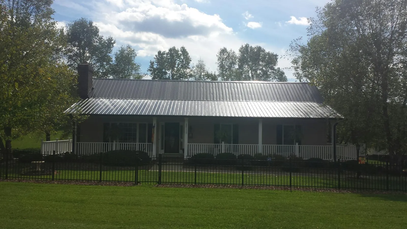Gray metal roof on a brick ranch with a full width front porch — Gutter Guard Installation work by our crew in Neshkoro