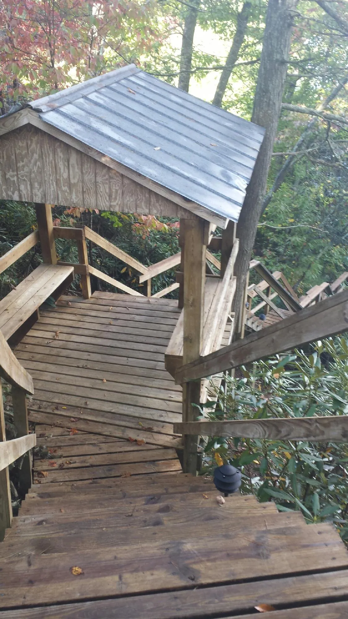 Metal roofed shelter over wooden steps on a wooded walkway — Skylight Repair & Installation work by our crew in Neshkoro