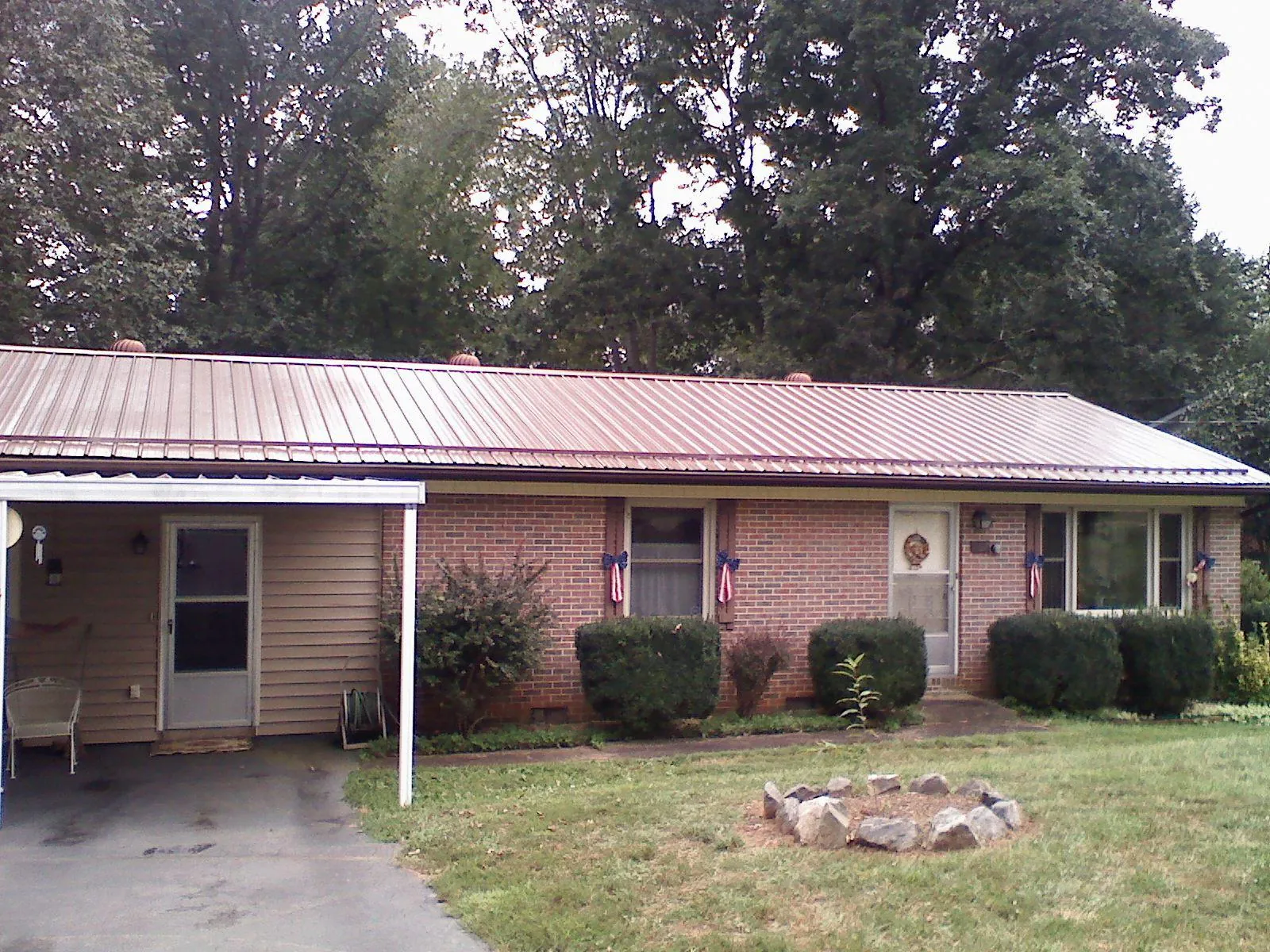 Bronze metal roof and carport on a brick ranch home — Roof Repair work by our crew in Neshkoro