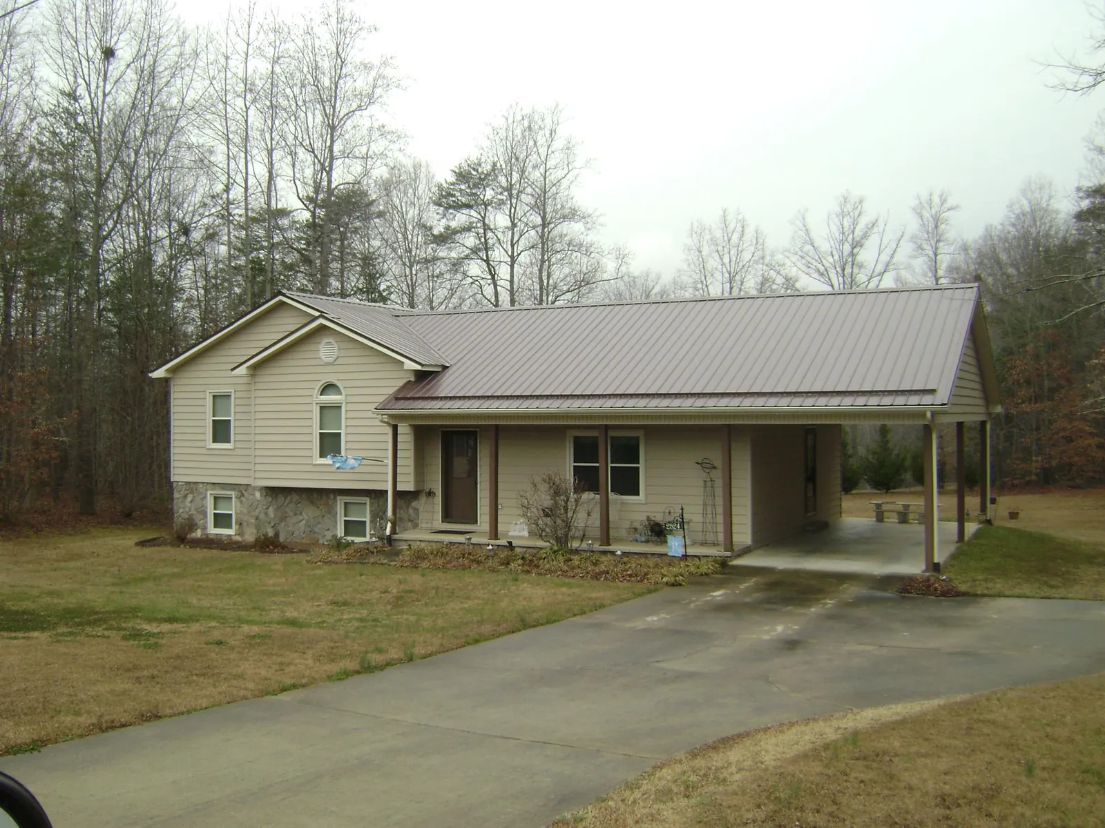 Brown metal roof on a tan split level home with an attached carport in Neshkoro
