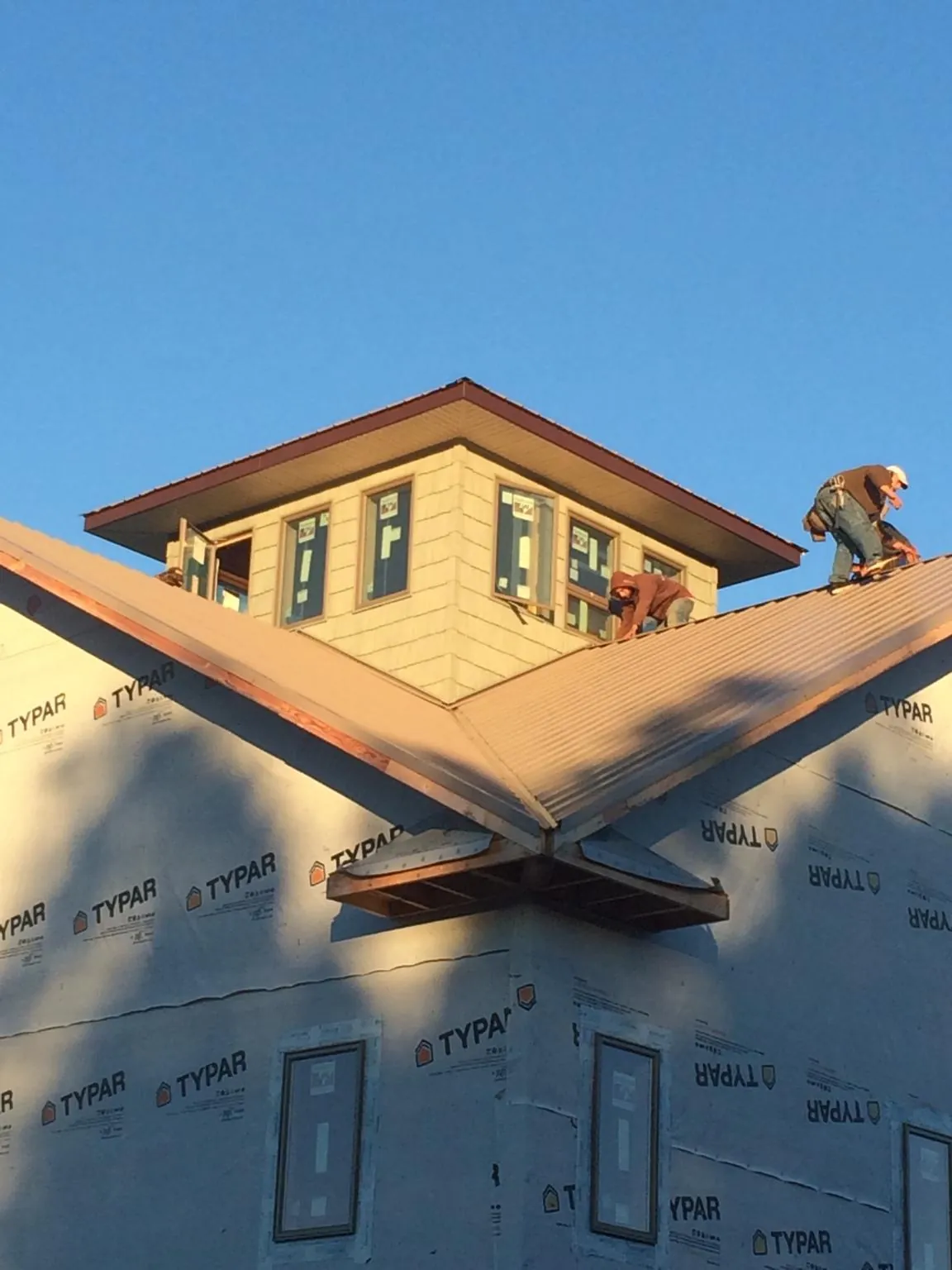 Roofers working around a rooftop cupola on a new metal roof at sunset — Roof Waterproofing in Neshkoro by Roofing Brothers